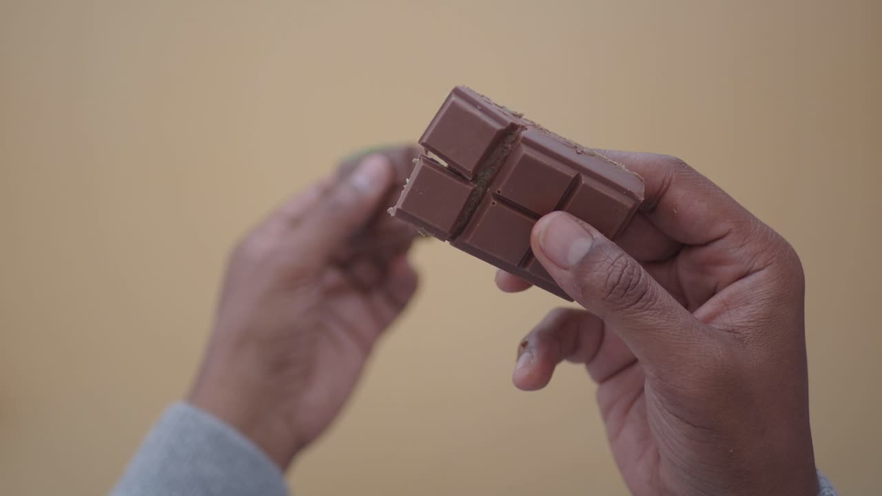 Hands breaking a chocolate bar with green filling