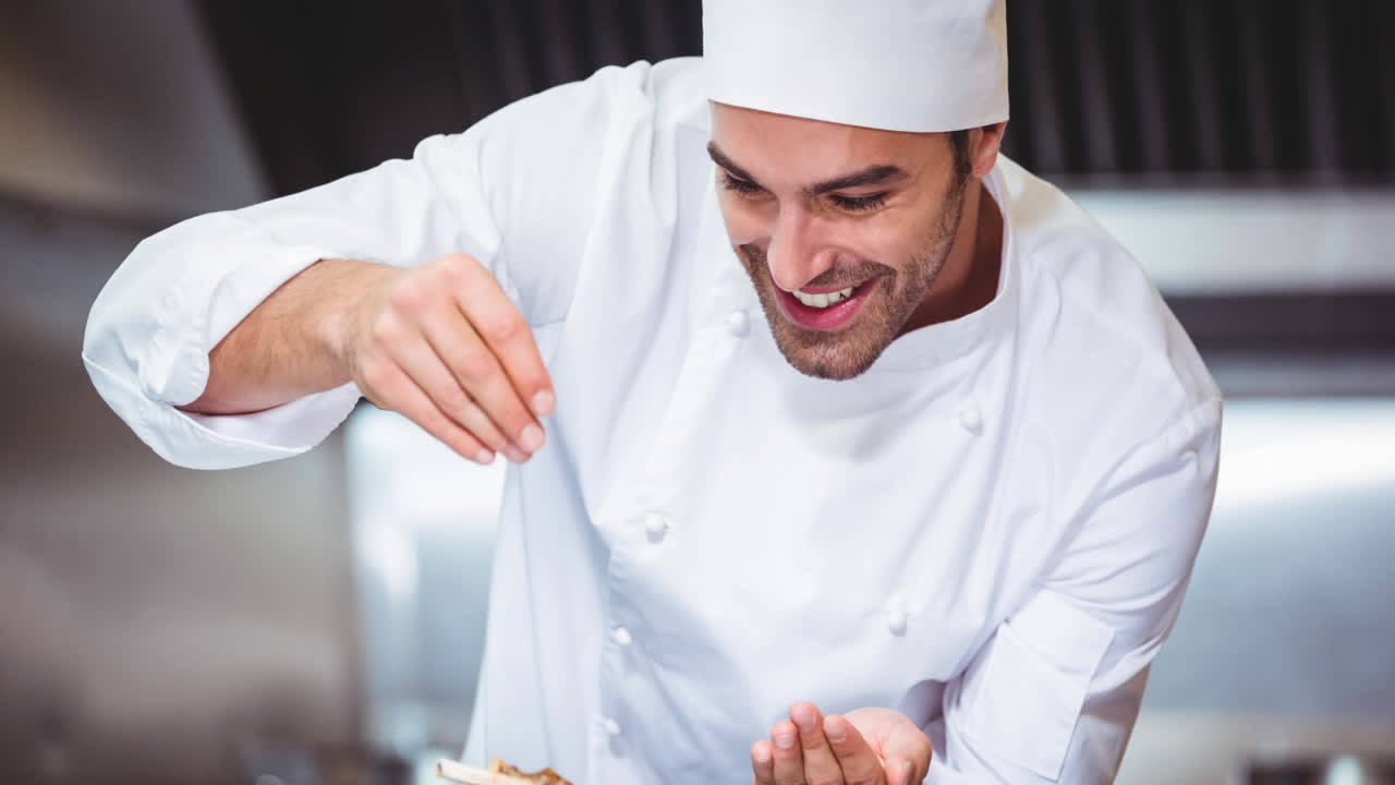 un chef caucásico sonriente con un delantal preparando comida en una cocina profesional