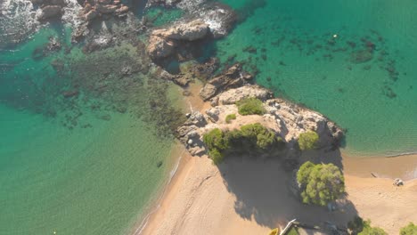 Aéreo,-De-Arriba-Hacia-Abajo,-Ojo-De-Pájaro,-Tiro-De-Dron,-De-Lado,-Sobre-La-Costa-Rocosa,-El-Mar-Turquesa-Y-La-Playa-De-Lloret-De-Mar,-En-Santa-Cristina,-Cala-Boadella,-Costa-Brava,-En-Cataluña,-España