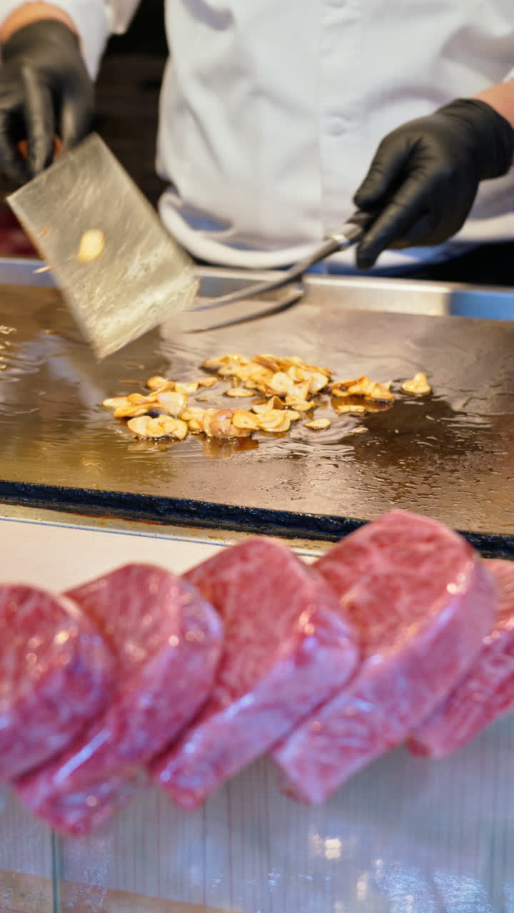 Close up of multiple pieces of Wagyu beef with a chef cooking in the background at the Tsukiji Fish Market in Japan. Vertical