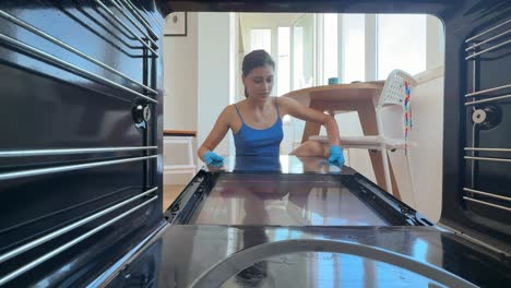 woman cleaning oven glass door