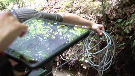 los científicos miden los datos de flujo de un río en suiza, escriben los resultados en una tableta