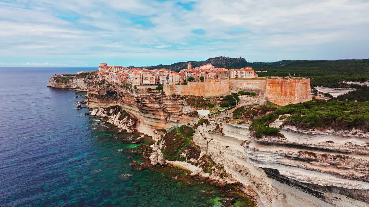 Aerial drone shot over the historic coastal town of Bonifacio in Corsica, France. High view of the rocky steep cliff and the turquoise sea. Ancient Citadel overlooking the rugged coastline