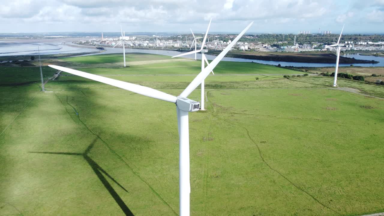 Aerial view flying around renewable energy wind farm wind turbines spinning on British countryside slow right dolly