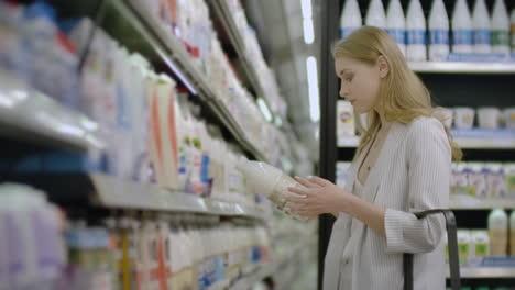 woman choosing and buying fresh organic dairy products at grocery store