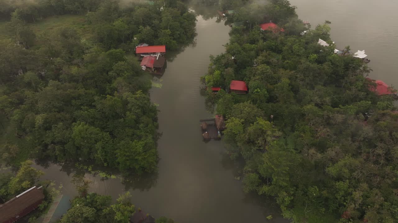volando sobre el río dulce guatemala con casas durante el amanecer, aérea