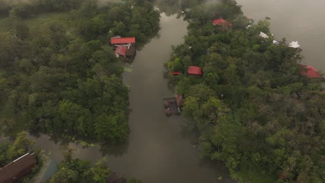 Volando-Sobre-El-Río-Dulce-Guatemala-Con-Casas-Durante-El-Amanecer,-Aéreo