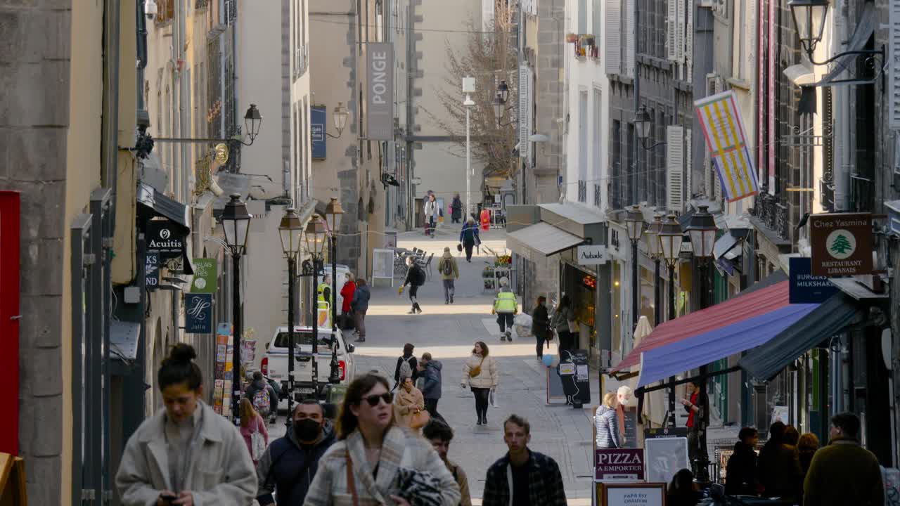 Camera tilts down to reveal people walking up an old narrow French street