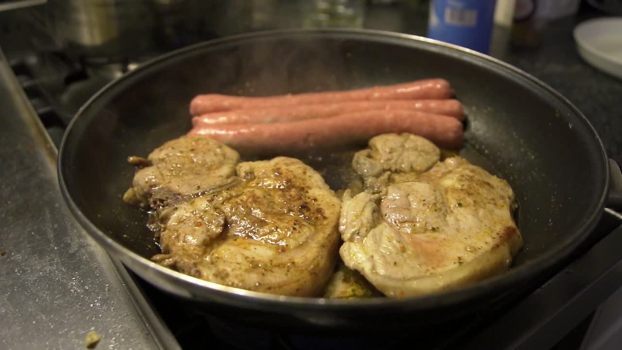 Padella sul fornello della cucina, carne che cuoce nel burro e aglio, salsicce e cotolette di latterino