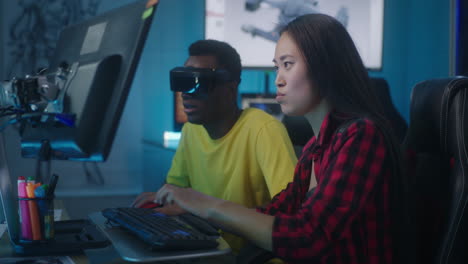 Two people working on a project in a computer lab with VR headsets