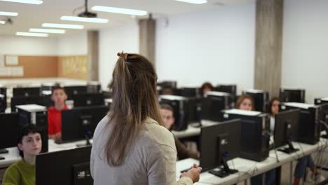 Female teacher working with students inside computer room at school