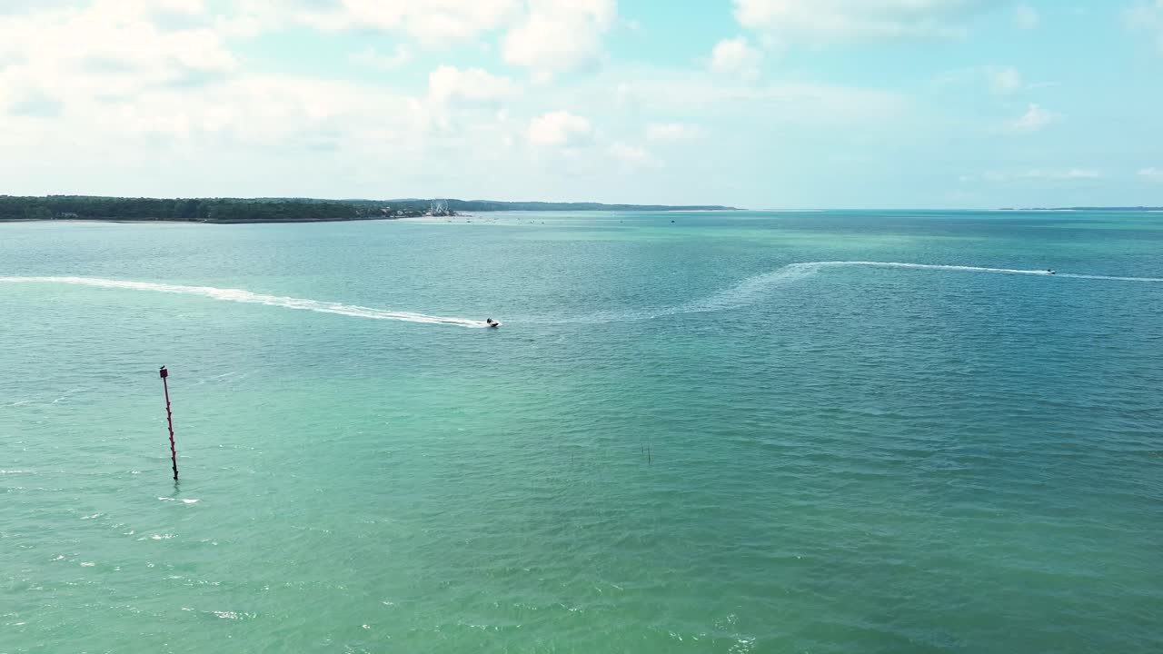 Drone footage capturing jetskiers carving dynamic paths across the turquoise waters of Charente-Maritime on a clear summer day