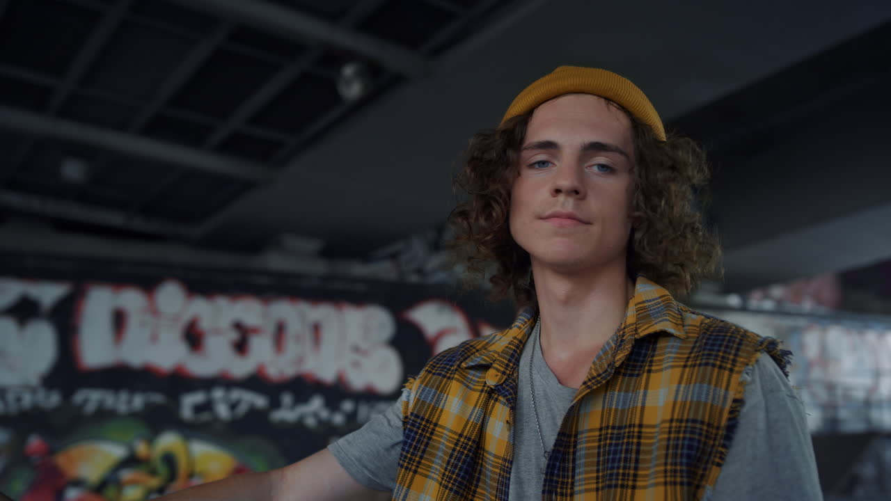 modelo atractivo posando para la cámara en el parque de skate. hombre de cabello rizado al aire libre.