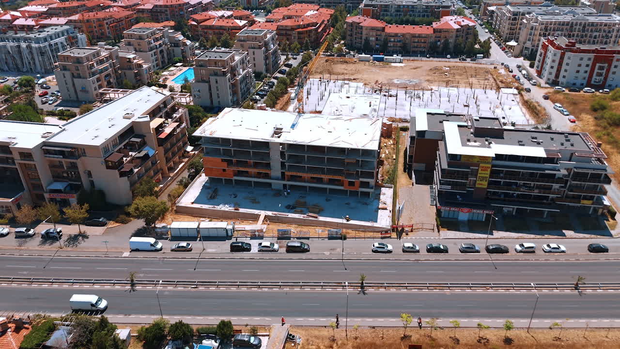 Construction site of a modern building in a coastal city. Drone view of an urban construction site surrounded by apartment buildings near the coast