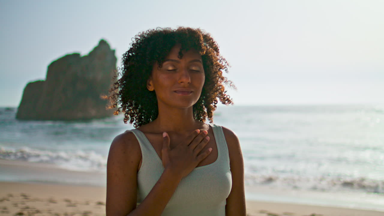 Peaceful woman meditating beach close up. girl putting hand on chest at sunrise
