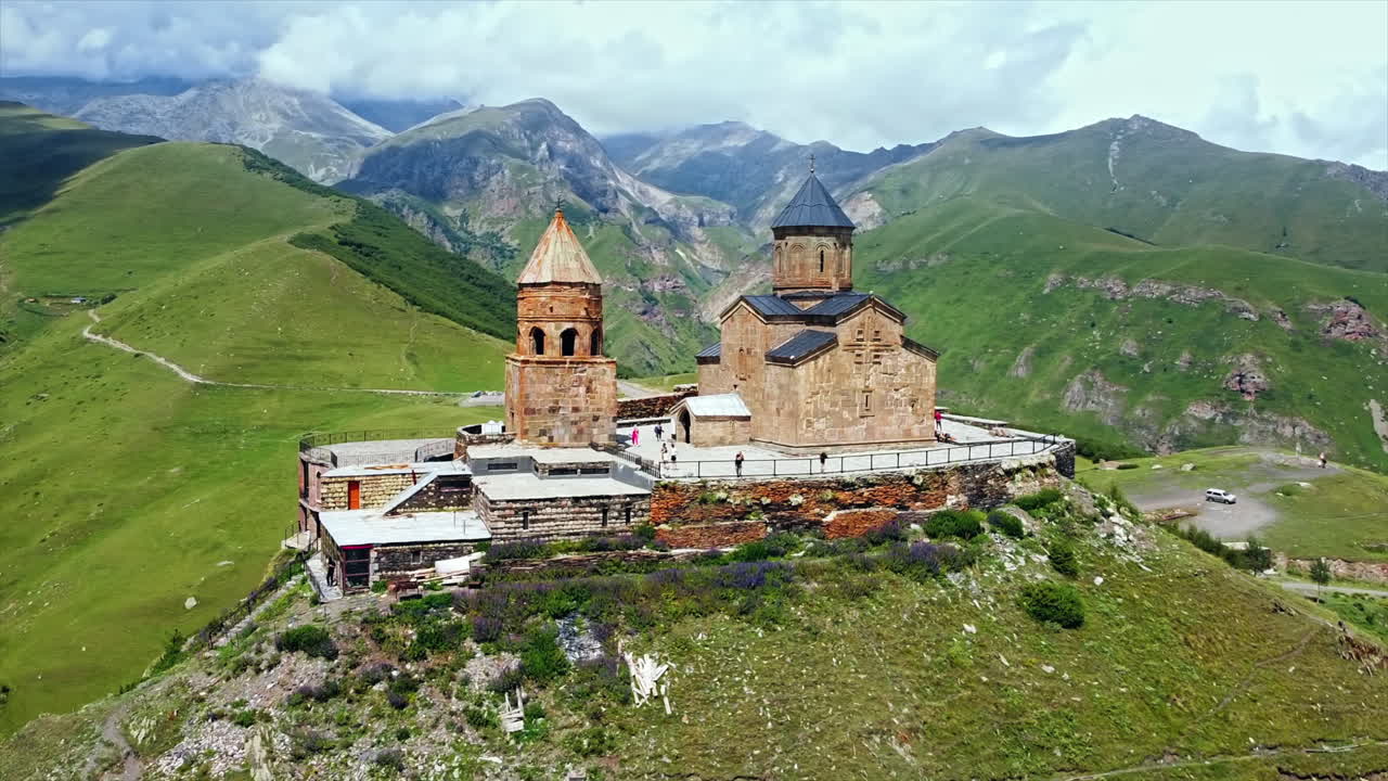 Aerial drone view of Gergeti Trinity Church in Georgia. Caucasus Mountains, church located on the top of a hill, greenery, valley