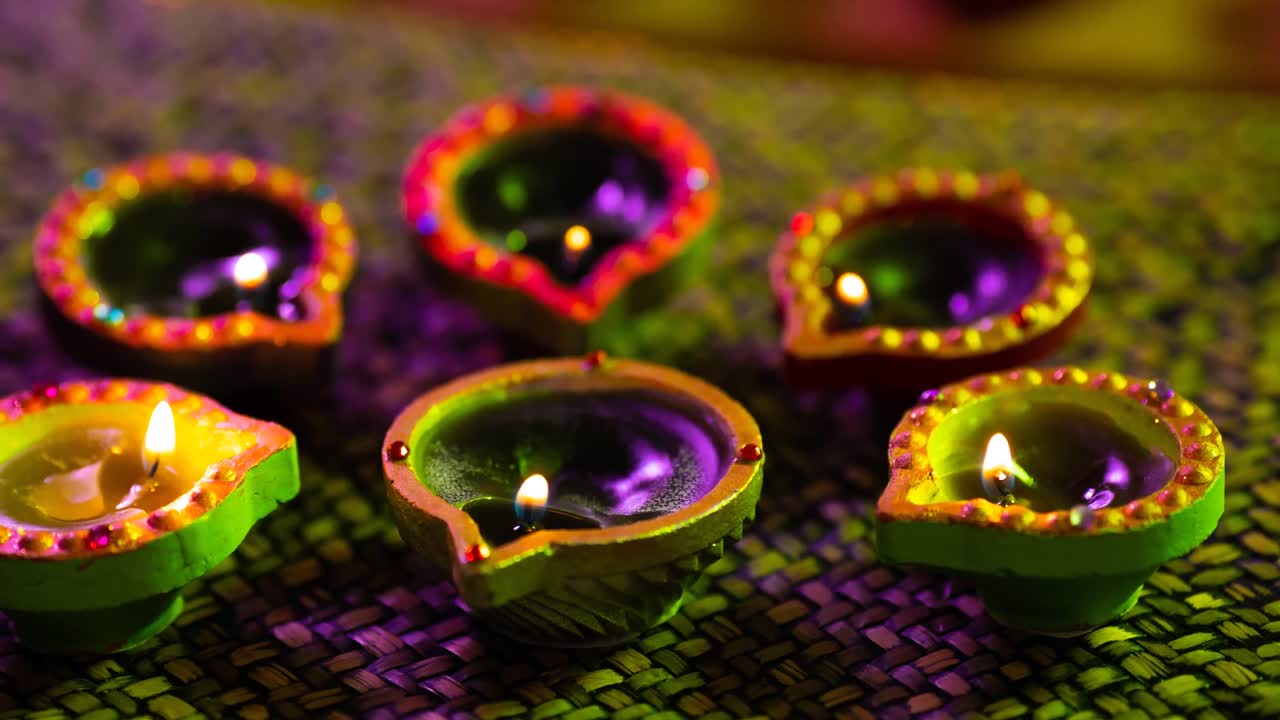 Video di candele Diwali accese e luminose in cerchio su superficie intrecciata viola-verde