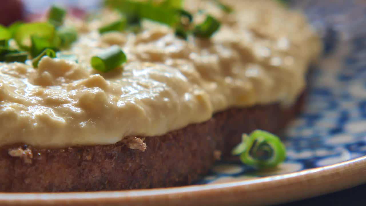 Primer plano de un sándwich con untable y cebolletas