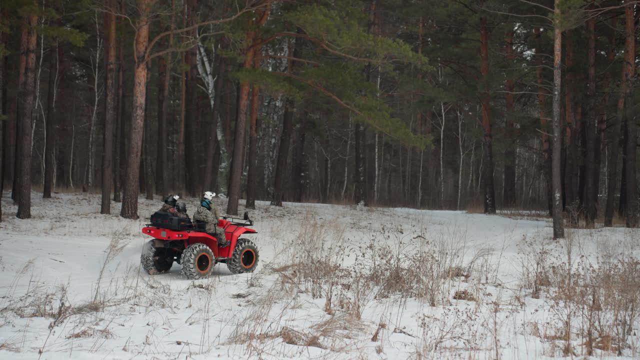 Quad rosso naviga un sentiero boschivo innevato con controllo preciso, pilota stile guardia forestale che affronta curve strette, pilota con casco bilancia acceleratore e freno, luce invernale attenuata attraverso i pini.