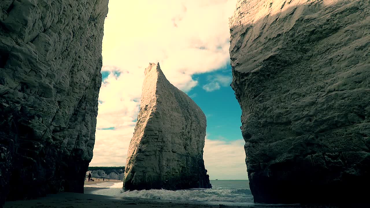 Slow motion footage showing towering chalk cliffs and distinct sea stack at Old Harry Rocks near Swanage in Dorset, England, with calm waves and bright sky creating dramatic coastal scenery