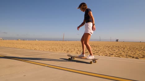 happy girl turning around while skateboarding on asphalt road in desert park