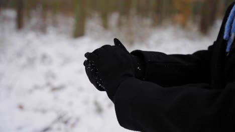 woman gets handful of snow and makes a snowball, camera close up