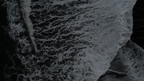 Birds-Eye-view-of-the-waves-coming-in-at-Reynisfjara-in-Iceland,-aerial