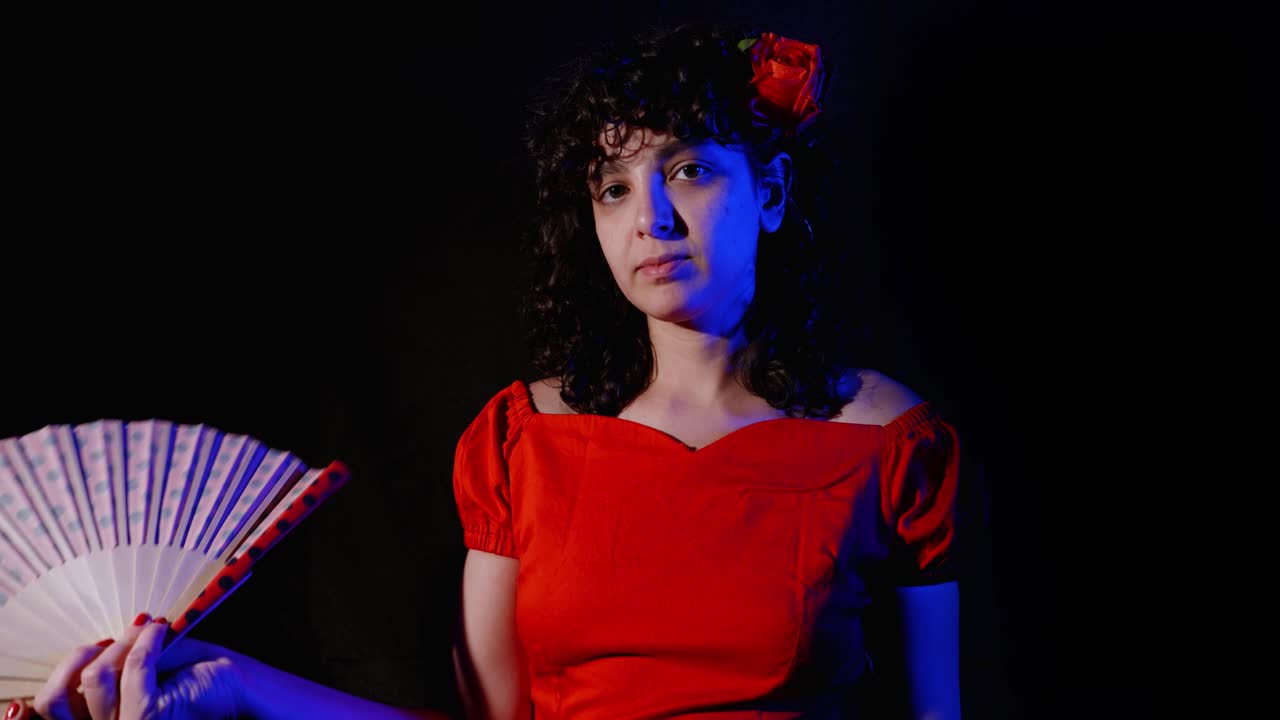 Giovane donna in abito rosso che si sventola con un ventaglio.