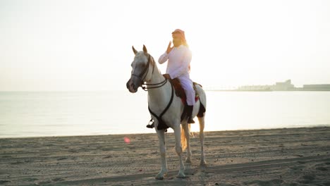 Ein-Ritter-Zu-Pferd,-Der-Die-Katar-flagge-Nahe-Dem-Meer-Hält-8