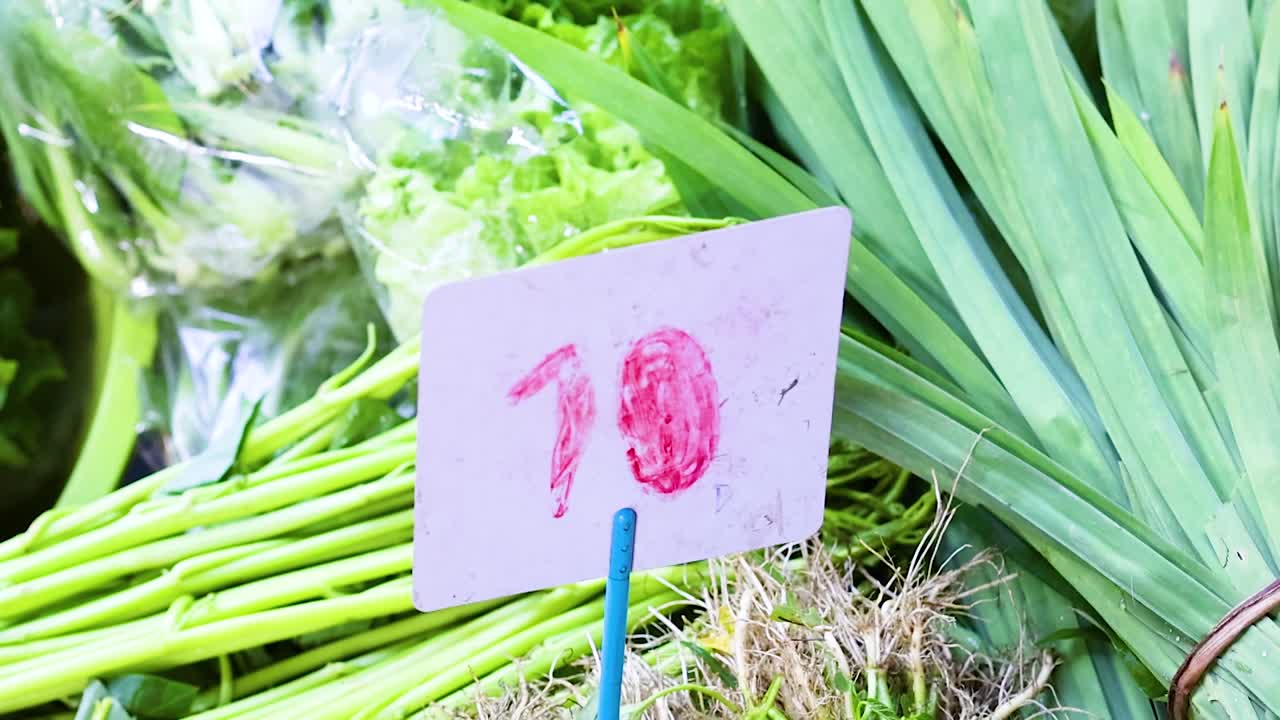 Bundles of fresh green vegetables with price tags, displayed in clear plastic bags.
