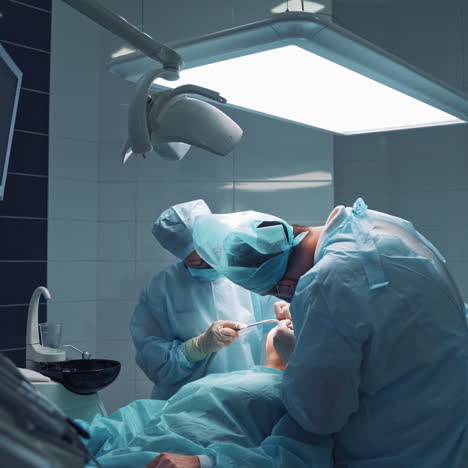 doctors in medical masks are doing tooth treatment in modern stomatology clinic. male professional dentist with his assistant at work. operation procedure.