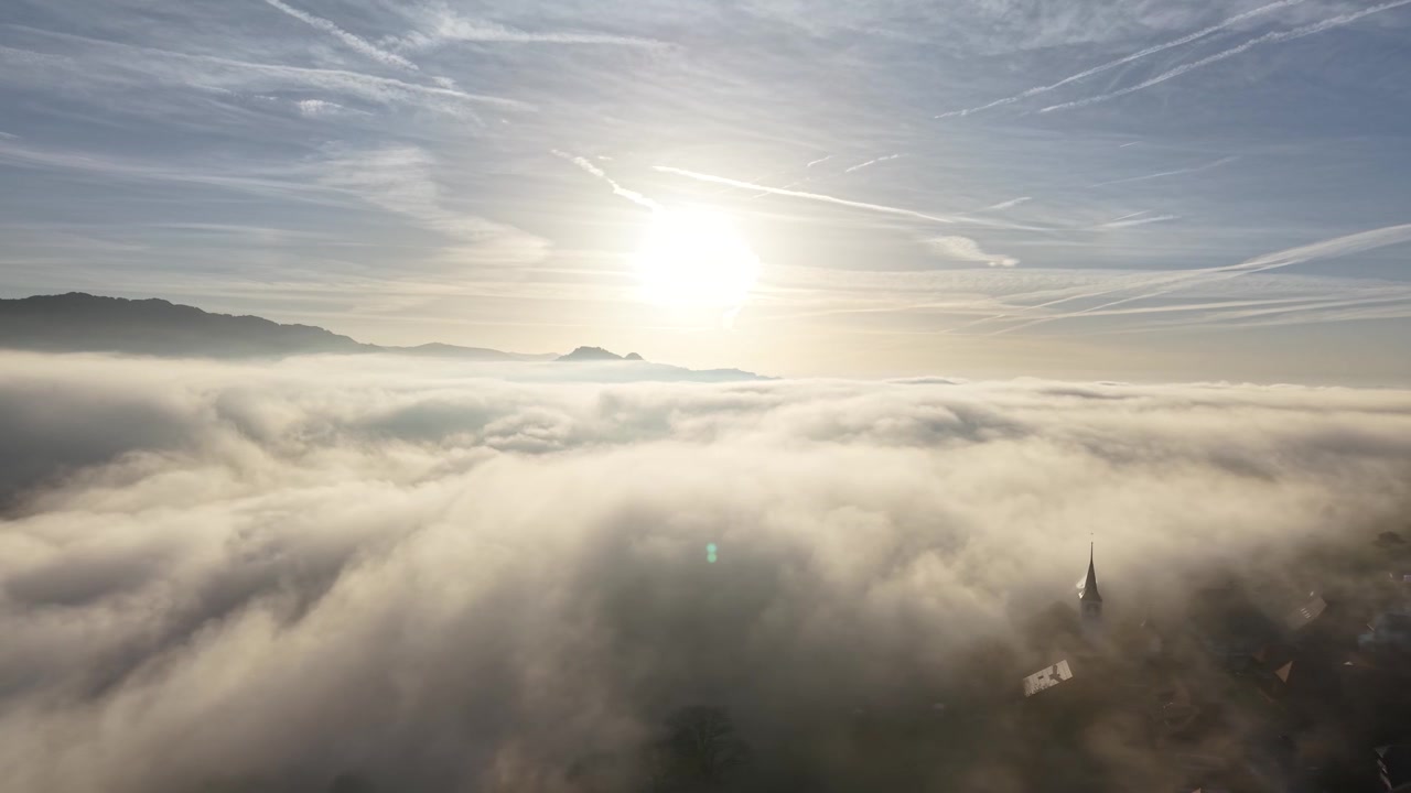 Riprese drone con sole basso sopra la nebbia e un piccolo villaggio. Girato con DJI Mavic Air 3s 4K 60fps 150mbit.