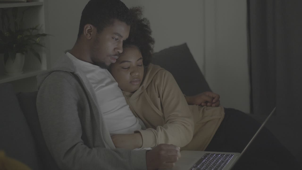 Young african american couple watching a film attentively on the laptop