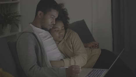 young african american couple watching a film attentively on the laptop