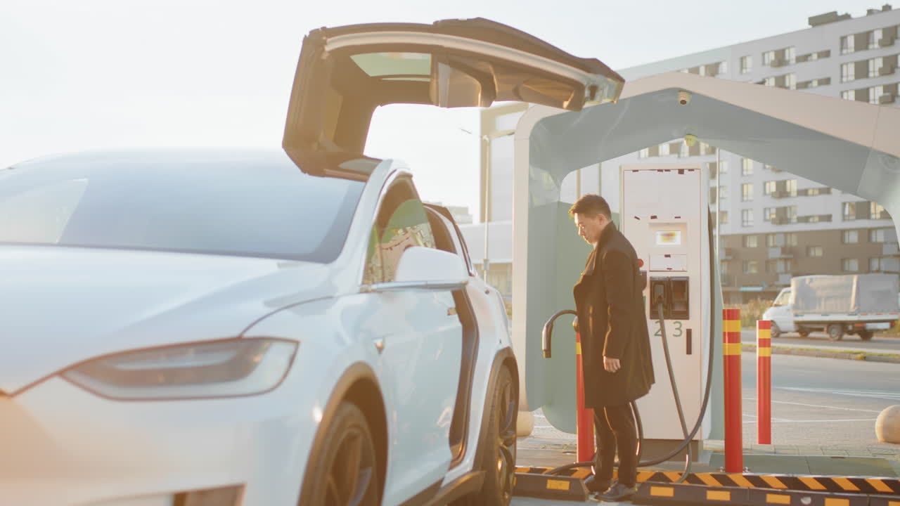 충전소 에서 전기 차량 을 충전 하는 사람