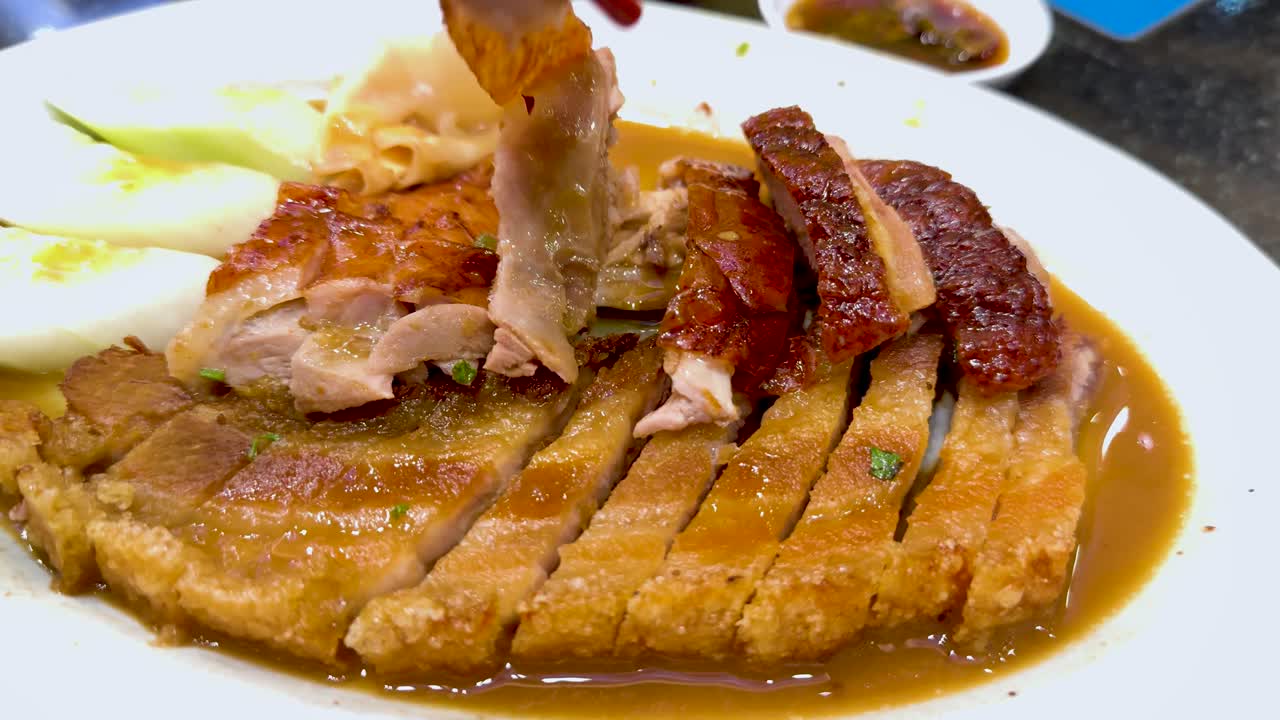 Chopsticks picking roast duck from a plate