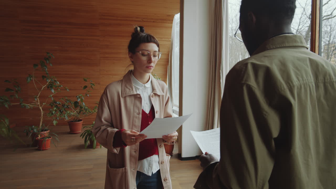 Woman Discussing Papers with Black Man in Library Hall