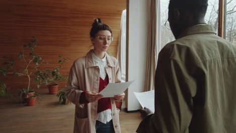 Woman-Discussing-Papers-with-Black-Man-in-Library-Hall