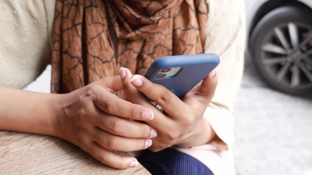 una mujer usando su teléfono en una mesa.
