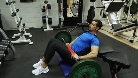 strong man performing hip thrusts inside a gym full of equipment