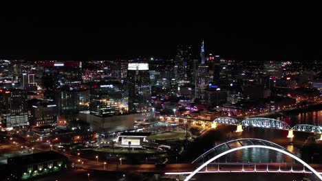 Aerial-view-of-john-seigenthaler-pedestrian-bridge-famous-bridges-over-cumberland-river-in-modern-city-at-night-drone-shot-4k