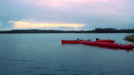 overlooking red canoe kayak on cold lake during sunset sunrise