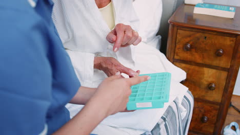 Close-Up-Of-Nurse-Helping-Senior-Woman-With-Medication-At-Home