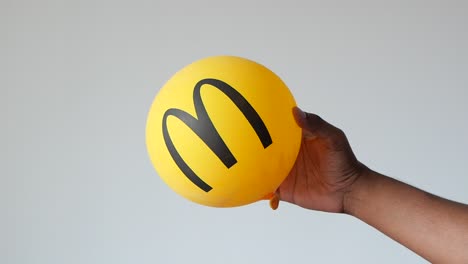 person holding a yellow mcdonald's balloon