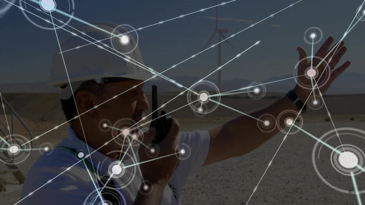 Field engineer speaking into two-way radio, raising hand and building wind farm network overlay