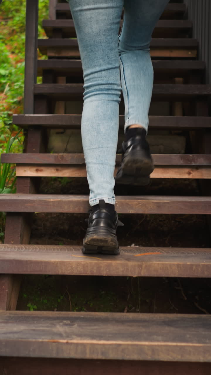 mujer sube las escaleras de la casa vista trasera. la señora vuelve a casa saltando después de relajarse durante la caminata en el área del bosque. el olor de agujas de pino y la tierra persiste en el aire