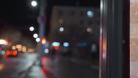 vista en primer plano de un panel de visualización con bokeh de luces de la ciudad en el fondo, con luces de automóviles borrosas y farolas