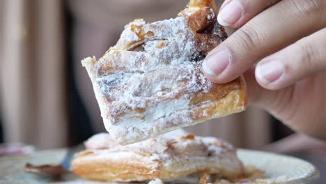 hand holding a piece of powdered sugar pastry