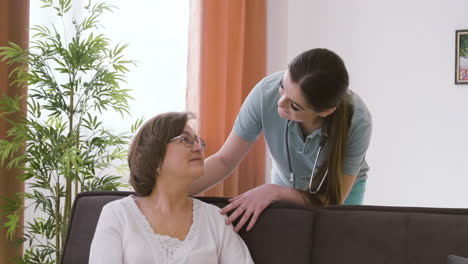 senior woman sitting on a sofa while talking to female doctor