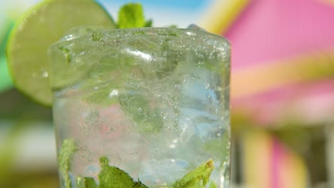 tilt up of mojito cocktail in tall glass with colorful background